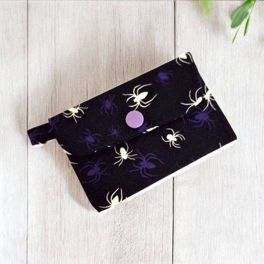Black pouch with spider design on a light wooden surface