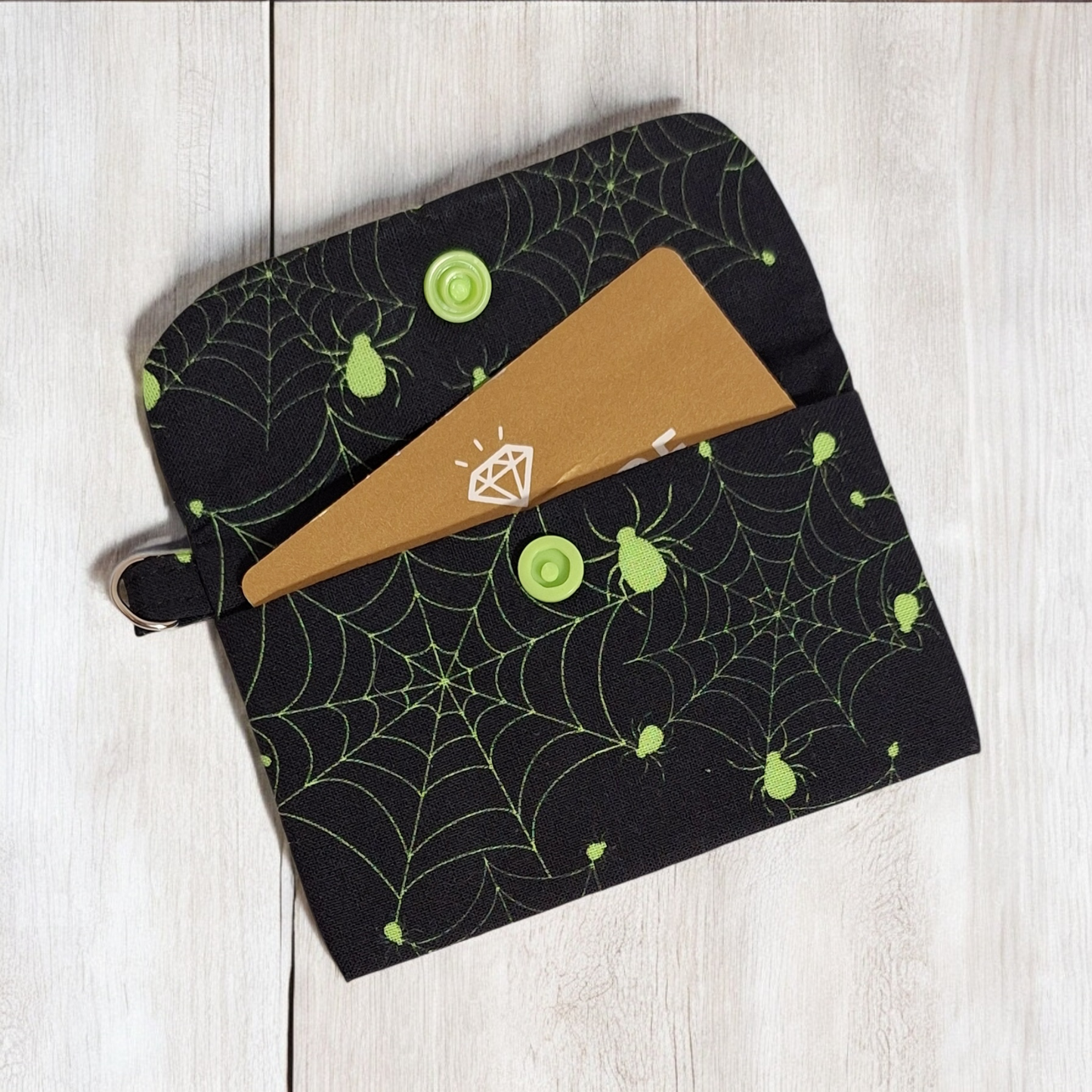 Black pouch with spider web pattern on a light wooden surface
