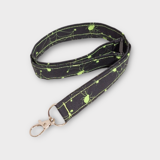 Black lanyard with green spider design on a light gray background