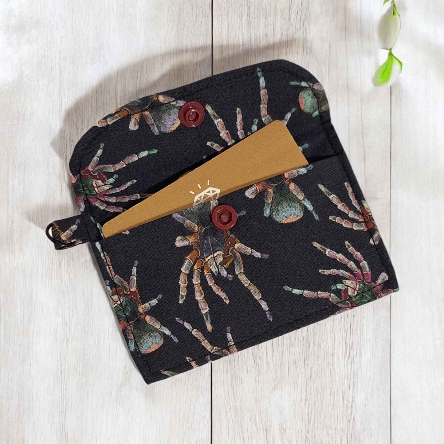 Fabric pouch with spider pattern on a light wooden surface