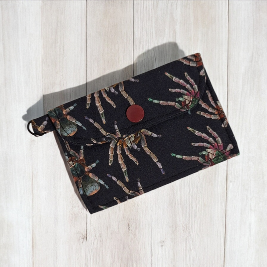 Black pouch with a spider pattern on a light wooden surface